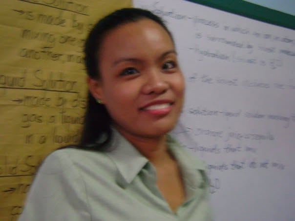Young woman smiling in front of a whiteboard during her early professional years in the Philippines
