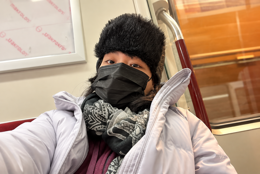 A woman bundled in winter clothes and a face mask while riding public transit in Canada.